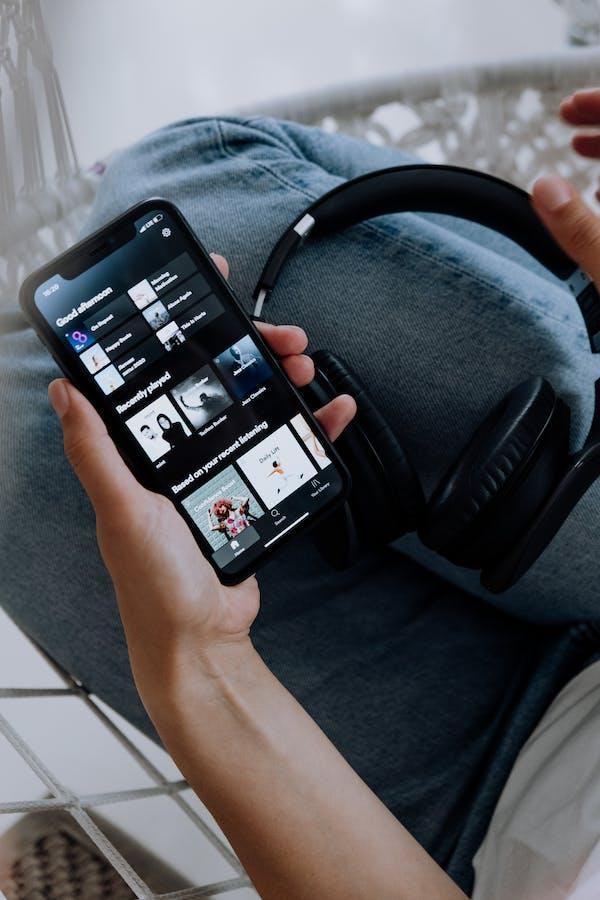 A person is holding a mobile phone showing he is listening music on Spotify