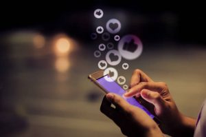 The image shows a person holding a mobile phone in her hands full of likes