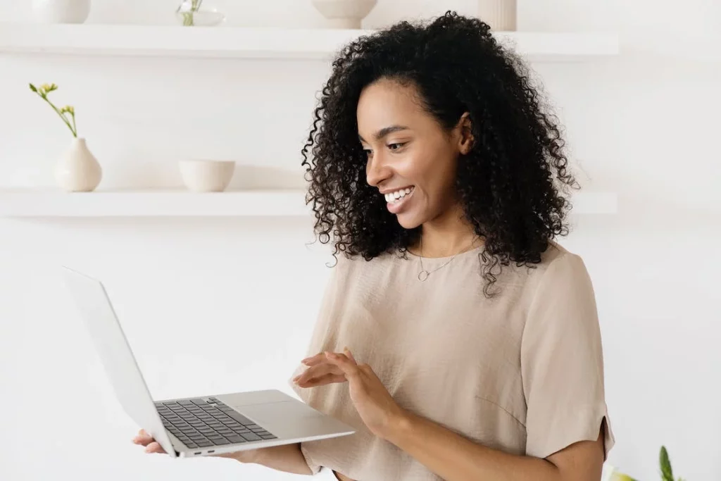Woman looking at the laptop screen makes a successful approval gesture