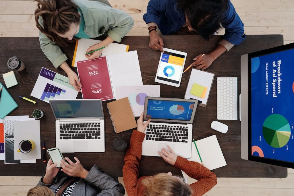 The image shows a group of people with their laptops working on digital advertisements