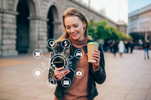 A person outside on the street is holding a mobile phone which shows some apps