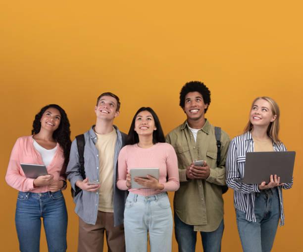 A group of persons smiling, most of them holding a portable device