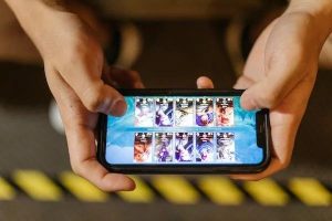 A person is holding a mobile phone and it shows games on the screen