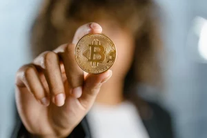 The image shows a woman showing a Bitcoin