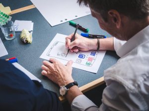 The image shows a person designing some apps on a paper