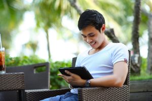 The image shows a person holding a tablet device and smiling