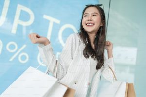 The image shows a satisfied customer. She is smiling and holding some shopping bags