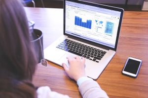 The image shows a person watching analytics on her laptop